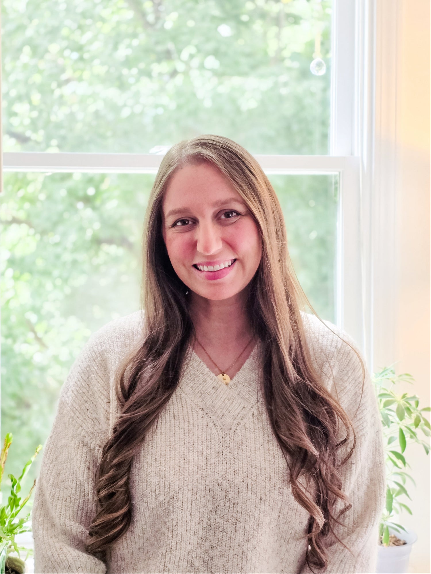 Image of Kelly Zayas Bass smiling in front of a window